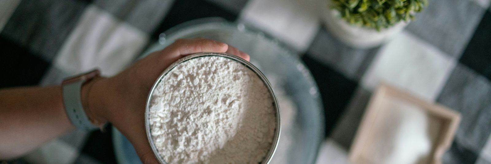 person holding silver round container with brown powder