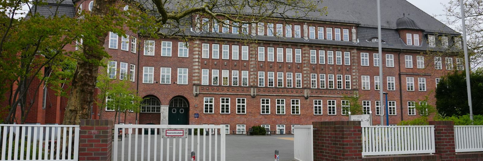 A large brick building with an open gate and trees