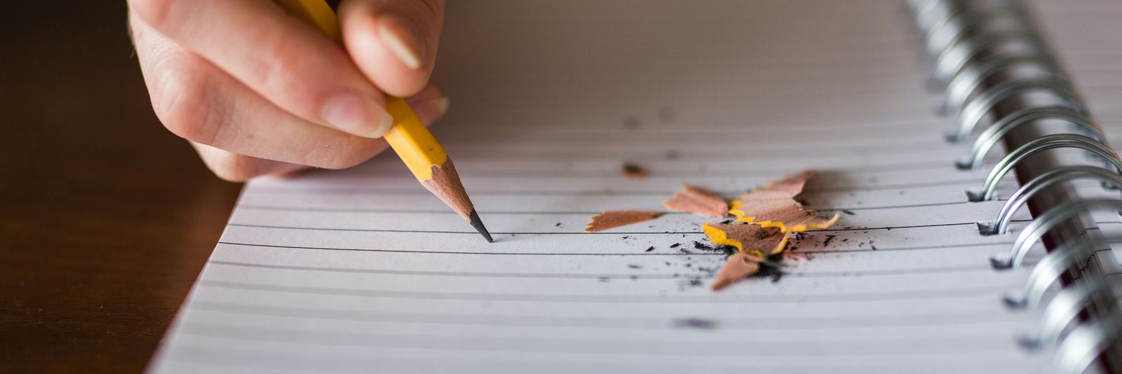 person holding pencil writing on notebook